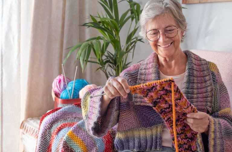 A senior woman enjoying knitting at a senior living community.