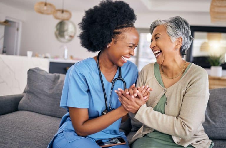 An older woman is smiling and having fun with her assisted living care aide.