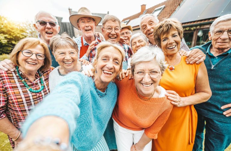 A happy group of older adults taking a picture together at an event in a senior living community.