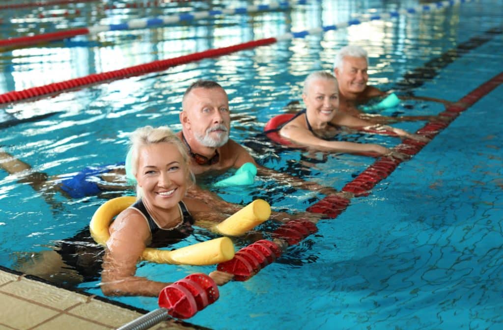 A group of older individuals are taking a group aquatic therapy class together.