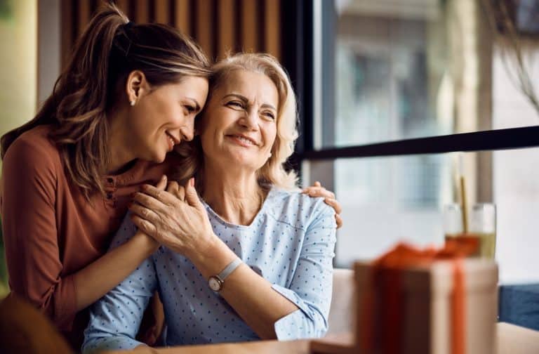 A daughter embraces her mature mother while visiting assisted living.