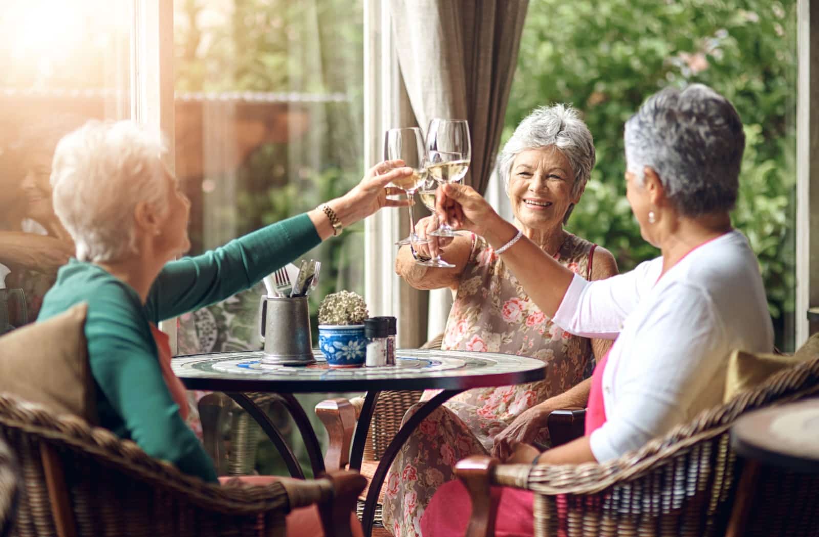 A friend group of three women happily connect at dinner while in assisted living.