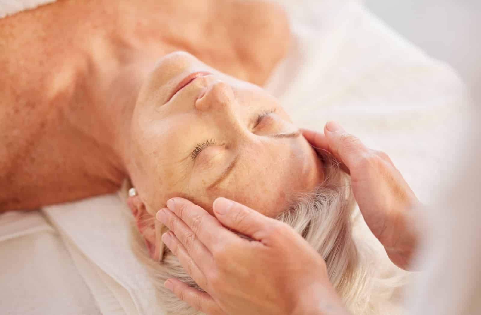 An older adult enjoys a head massage at an assisted living community's full-service spa.
