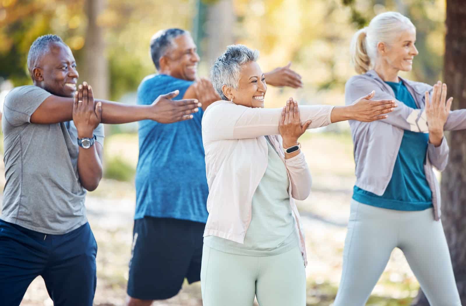 A group of happy-looking seniors participating in a personal trainer-led group fitness class together.
