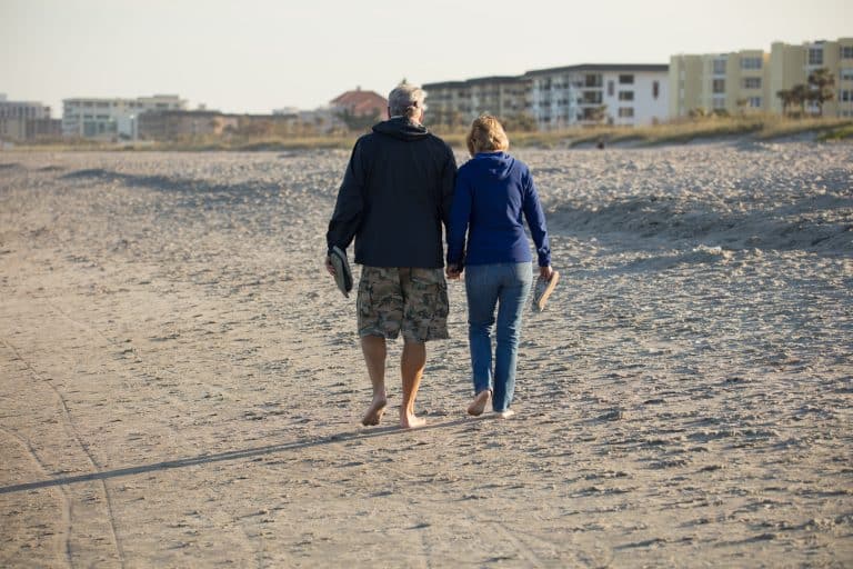 A senior couple walks together along a beach