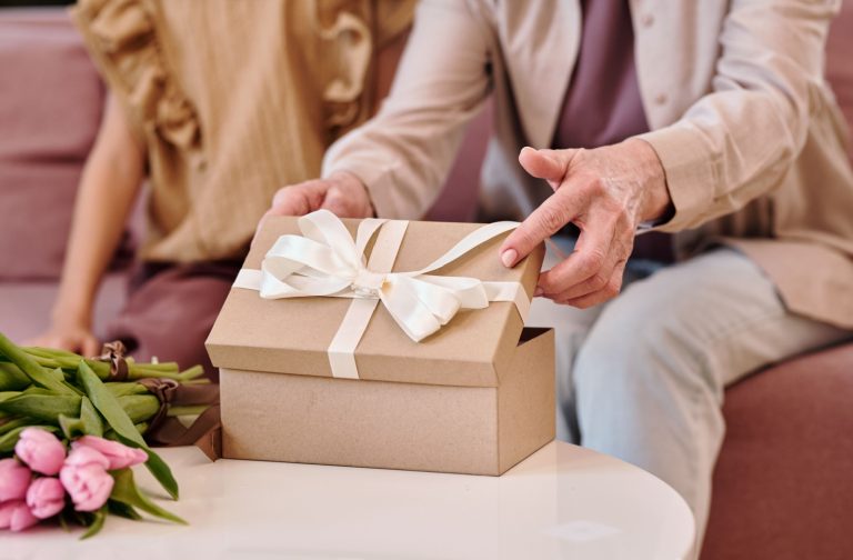 A close-up image of a senior opening a thoughtful gift from their grandchild.