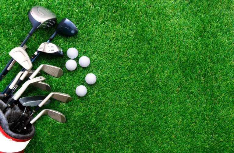 Golf clubs and golf balls arranged on vibrant green grass, highlighting equipment designed for senior golfers.