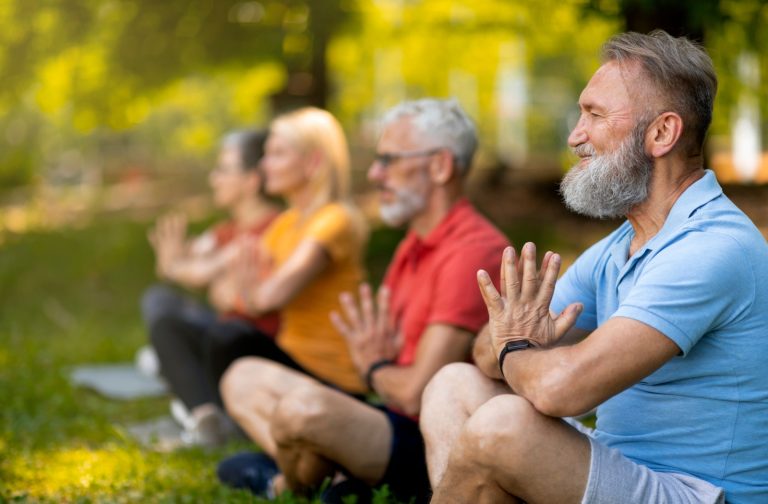 A group of seniors meditating and practicing relaxation techniques together in the park.