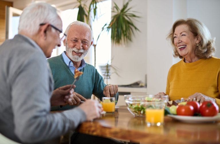 A group of older adults laughing and dining together.