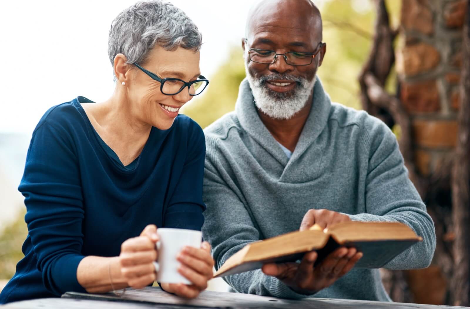 A senior sharing a section of a book with a friend in an assisted living community, both smiling and engaged in conversation.