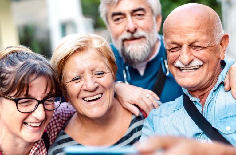 A group of smiling seniors on a day trip take a photo together.