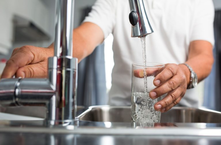 A senior pours tap water into a glass, secure in knowing that an integrated filtration system will provide clean water
