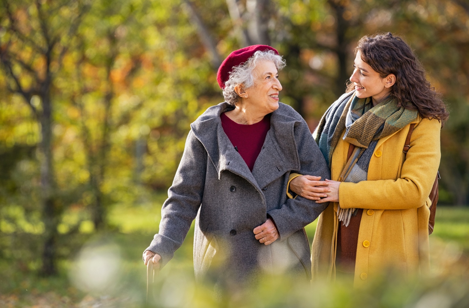 A senior enjoys a walk outside with their adult child.
