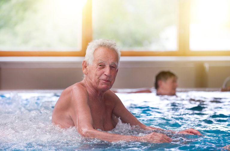 Older adult relaxing in warm water with massage jets during a hydrotherapy recovery session.