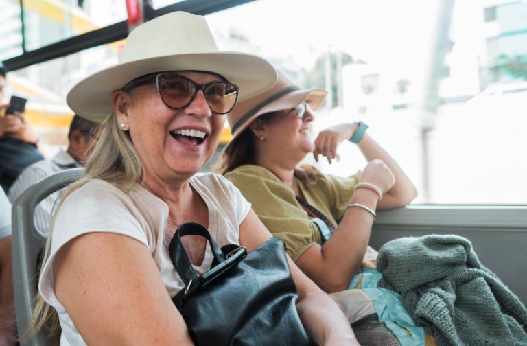 Older adults laughing together on a bus during a social group excursion, promoting cognitive health.