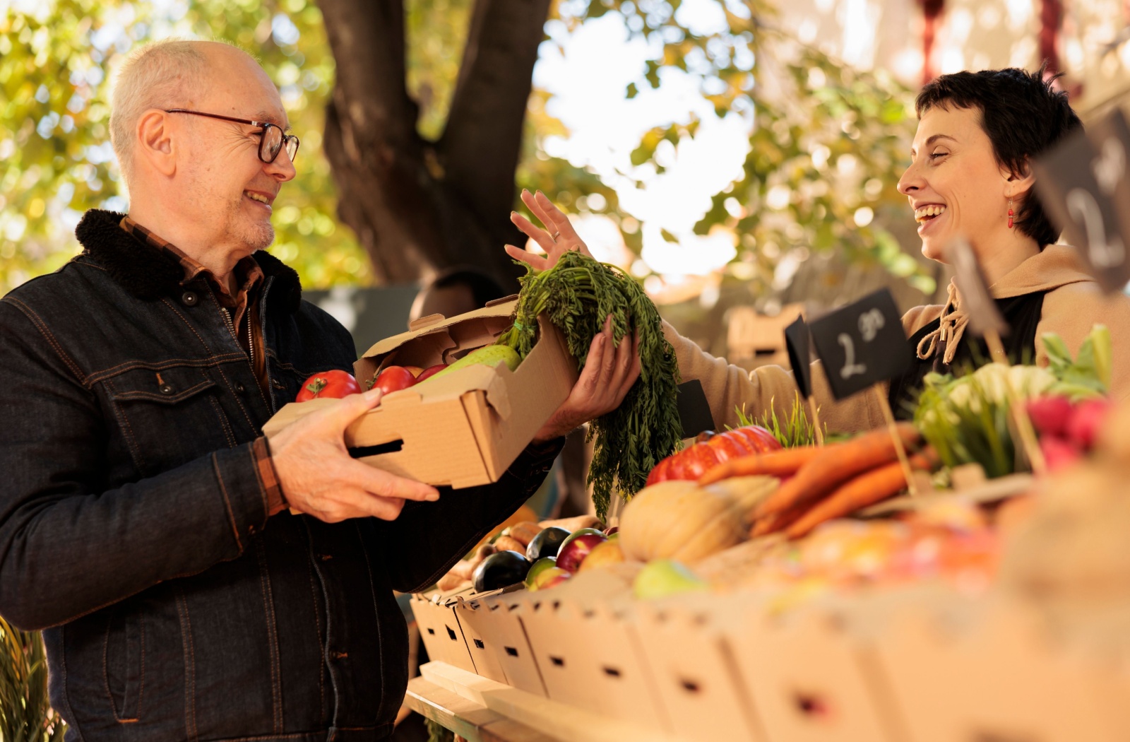 A smiling older adult buys fresh produce from a stand at the farmer's market.