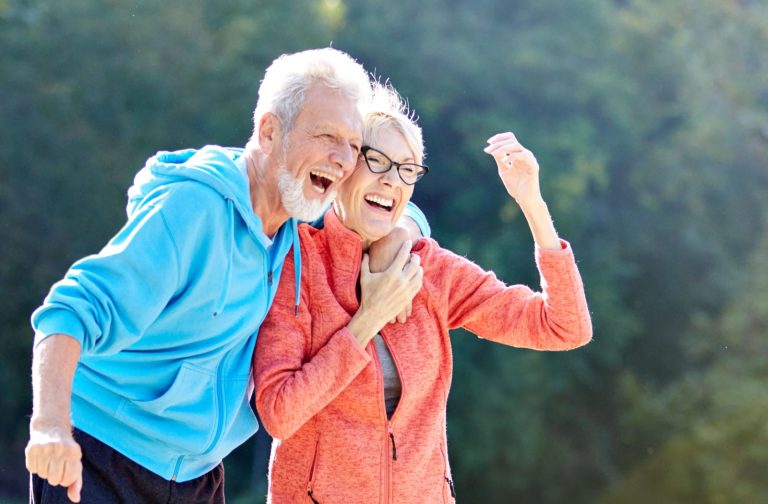 Older adults laughing together during outdoor exercise in park setting enjoying active aging fitness and joyful senior wellness