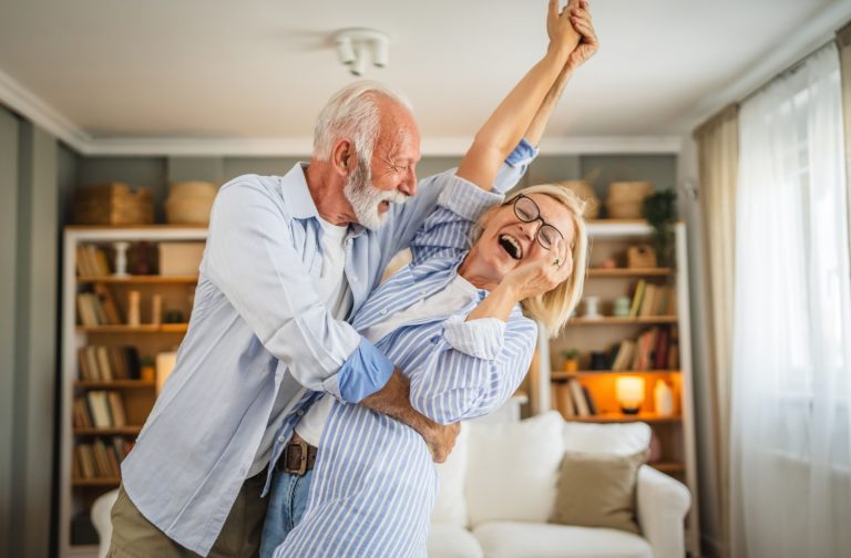 Active senior couple dance and enjoy together life together in their apartment in their rental community.