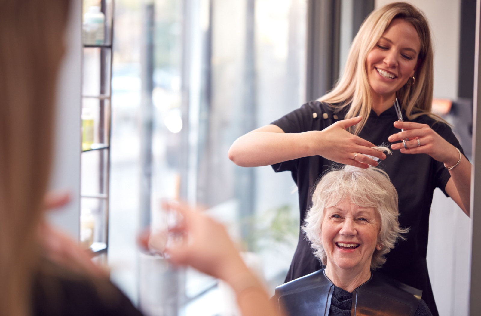 A senior has their hair cut by a stylist in a beauty salon in their active adult living community.
