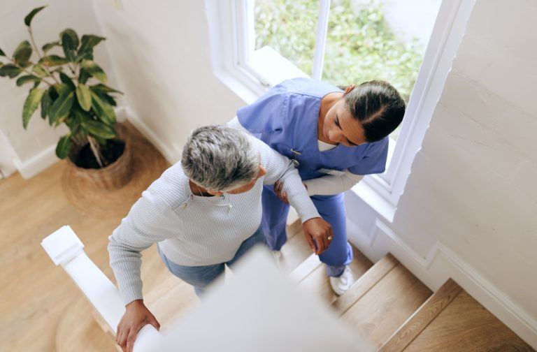 A caregiver assists an assisted living resident up a flight of stairs