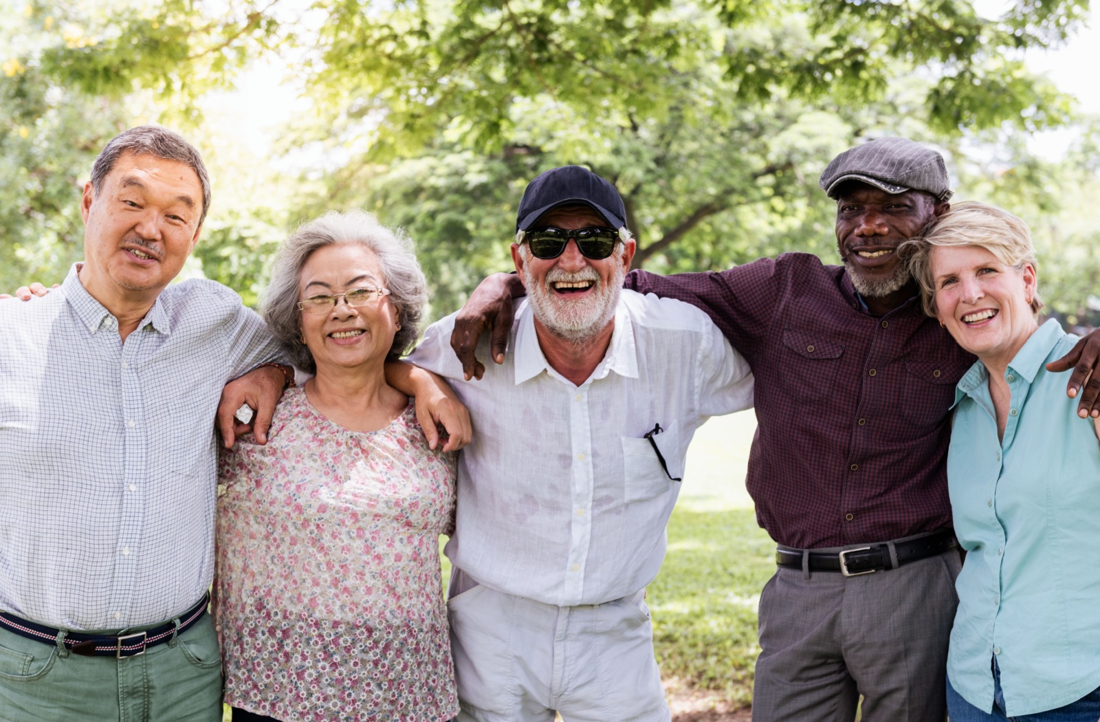 A group of 5 senior friends embrace each other while smiling for a photo