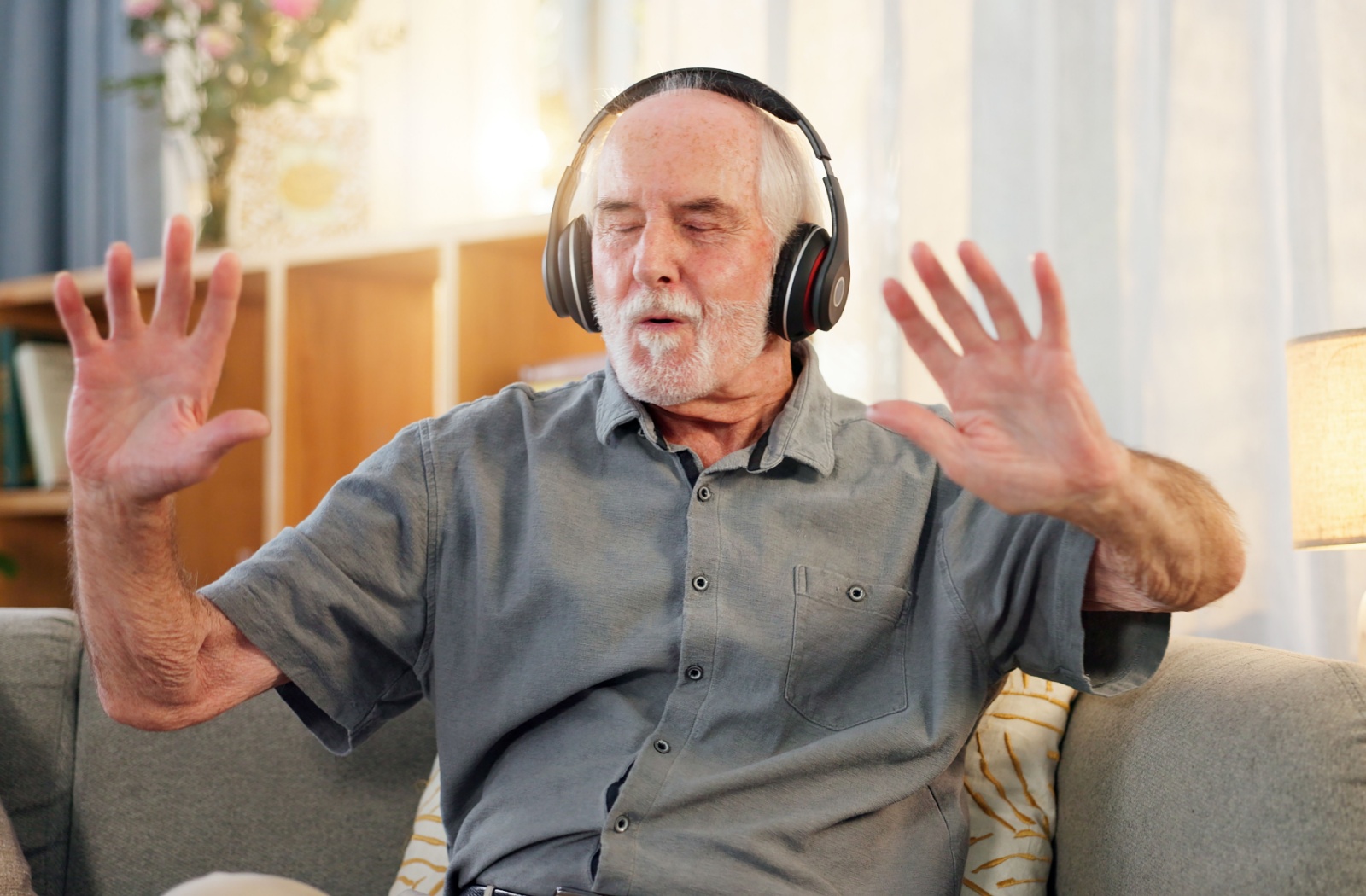 A senior relaxes with their favorite music playing through some wireless headphones.